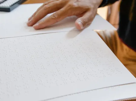 Una persona legge in braille alla scrivania con un portatile